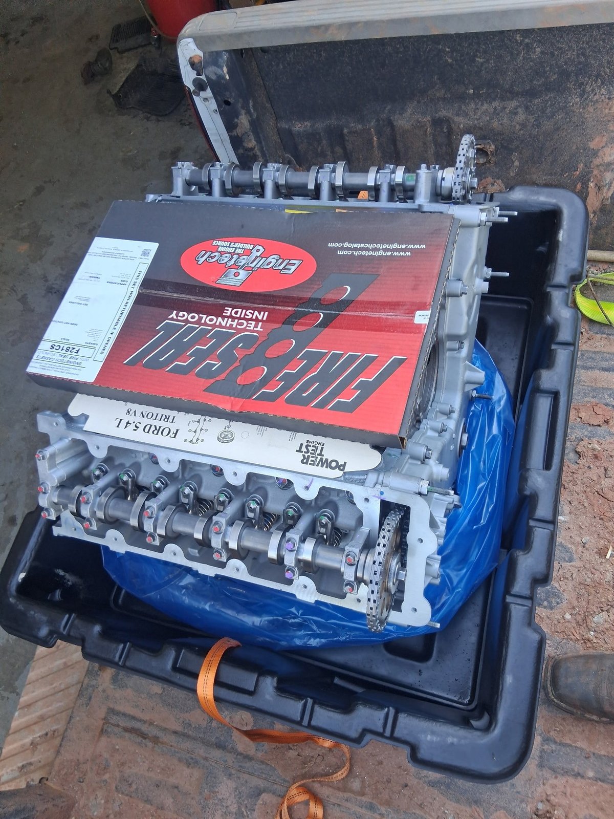 Overhead view of a blue and white car engine with red tool organizer on a black plastic engine stand